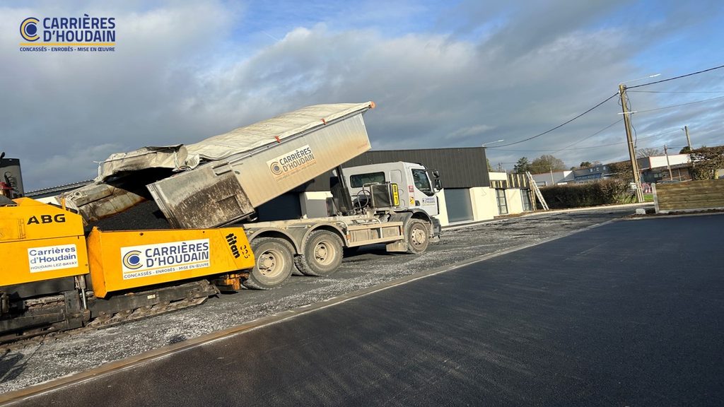 Camion benne Carrières d’Houdain déversant l’enrobé dans le finisseur sur un chantier de parking