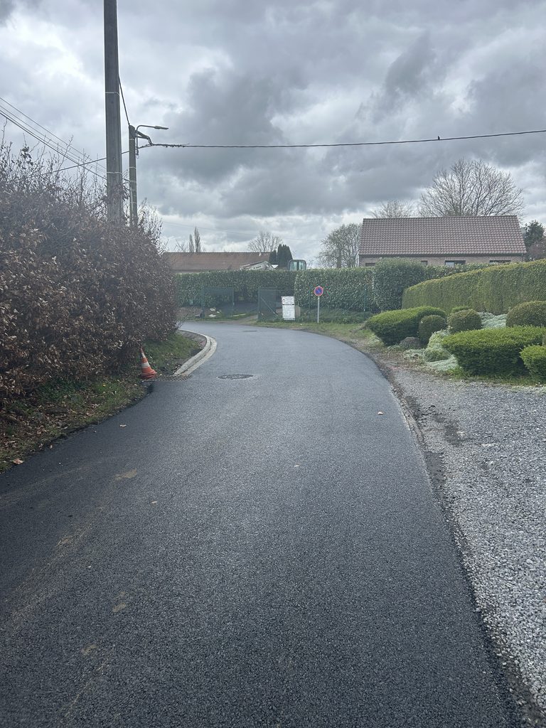 Couche de roulement en enrobé BBSG 0/10 terminée, avec caniveau en bord de chaussée